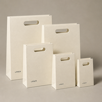   Sac en papier de luxe découpé avec poignée, logo gaufré à l'or et ruban pour emballage cadeau de bijoux, cosmétiques et boutiques