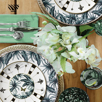 Ensemble d'assiettes en porcelaine avec feuilles tropicales, rayures radiales noires et blanches et motifs géométriques avec accents dorés