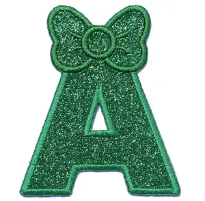 刺绣大写字母A至Z闪耀闪光字母，蝴蝶结为圣诞绿色，背衬为女孩的裙子