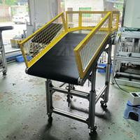 Convoyeur à bande plate inclinée AST avec garde-corps et bande antidérapante pour la manutention de pièces en plastique et de composants métalliques après la préhension par robot
