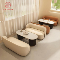 Ensemble de mobilier de café avec canapé incurvé beige brun en cuir et table ovale en marbre pour restaurant
