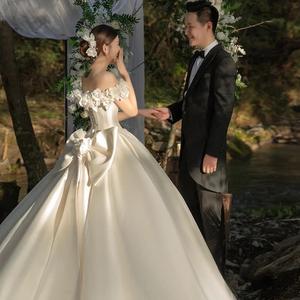 Váy cưới trắng lệch vai kiểu dáng mới sang trọng, chất liệu satin, đuôi dài, thiết kế lưng buộc dây và trang trí hoa. - Product Image 4