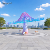 Grande sculpture champignon interactive d'extérieur à dégradé de couleurs, chaise suspendue en treillis rose, violet, bleu, pour place en bord de mer, personnalisable