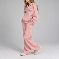 Ensemble deux pièces sport streetwear pour femme : sweat à capuche oversize zippé à épaules tombantes et pantalon de survêtement large brodé avec patchs rétro