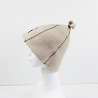 Un chapeau de sauna en pure laine beige qui équilibre la vapeur avec un emblème Yin Yang qui profite de chaque côté de la chaleur