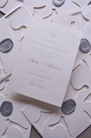 Suite d'invitations de mariage de luxe élégante en carton texturé gaufré avec lettrage en relief, motif floral blanc gravé, et carte RSVP détaillée