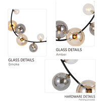 Lustre décoratif en forme d'arbre artistique à branches, avec globes en verre de tailles variées et structure en métal noir, idéal pour hall à plafond haut