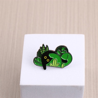 Épingle en émail de créature de forêt enchanteresse-Figure noire parmi les feuilles vertes. Un accessoire fantaisiste pour les amoureux de la nature
