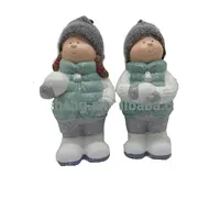 ฤดูหนาวนั่งเด็กชายและเด็กหญิงรูปแกะสลักกับก้อนหิมะในมือ