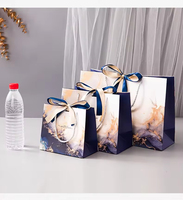 Sac cadeau en papier marbré bleu de luxe personnalisé avec poignée en ruban pour l'emballage de vente au détail