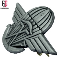 Badge métallique personnalisé en forme d'ailes, fabriqué au Gabon