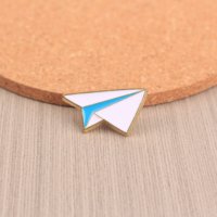 Broche en émail élégante et simple avec un design d'avion en papier, adaptée aux personnes soucieuses de la mode dans une esthétique minimaliste.