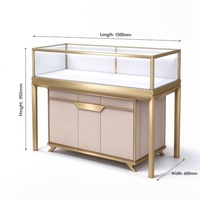 Comptoir de présentation de bijoux en verre avec cadre doré et armoire de rangement en similicuir pour la vente de bijoux de luxe