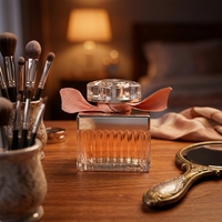Parfum pour femme, flacon rectangulaire en verre côtelé, collier argenté, capuchon transparent, nœud doré, liquide floral longue durée