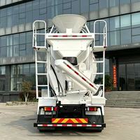 Camion malaxeur à béton avec cuve de mélange blanche et chute de déchargement arrière pour la livraison de béton prêt à l'emploi