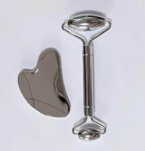 Set de masaje compuesto por rodillo facial y placa de gua sha fabricados en acero inoxidable - Product Image 1
