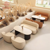 Ensemble de mobilier de café avec canapé incurvé beige brun en cuir et table ovale en marbre pour restaurant