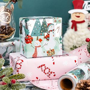 Papel de regalo navideño de doble cara con diseño de muñeco de nieve y árbol de Navidad en verde y rosa, con patrón de letras y revestimiento de aluminio. - Product Image 1
