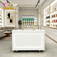 Bar à parfums de luxe moderne avec distributeurs en verre suspendus à cadre métallique doré, dotés d'un design LED écologique pour les magasins de détail haut de gamme
