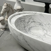 Baignoire ovale autoportante en marbre de Carrare italien avec rebord épais et arrondi et siège intérieur profilé pour projet de salle de bain de penthouse