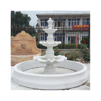 Fontaine ronde en marbre blanc sculptée à la main avec des pots de fleurs et une statue de nymphe