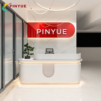 Comptoir de réception moderne en terrazzo pêche avec panneau mural rétroéclairé par LED bicolore et design contemporain pour hall d'accueil