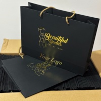 Sacs shopping en papier noir mat élégants avec logo personnalisé, impression dorée à chaud, et poignées en ruban pour l'emballage de perruques en boutique