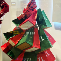 Sacs en papier kraft empilés de manière créative en forme de sapin de Noël, ajoutant une touche festive à l'affichage des magasins de vêtements