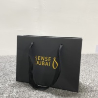 Sac de shopping personnalisé en papier kraft noir de luxe laminé avec logo en feuille d'or et poignée en ruban pour l'emballage de vêtements et de chaussures