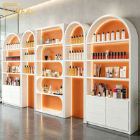 Étagère de présentation moderne pour cosmétiques orange, aménagement de magasin de soins de la peau, éclairage LED, rangement mural arqué pour centre de beauté commercial