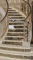 Escalier courbé classique avec des motifs en fer forgé sur mesure, marches en bois et en marbre