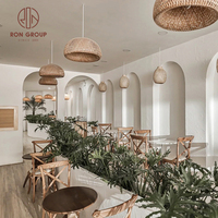 Ensemble de mobilier de restaurant au design naturel moderne : chaises en bois à dossier croisé, table ronde en marbre, banquette en tissu pour usage commercial