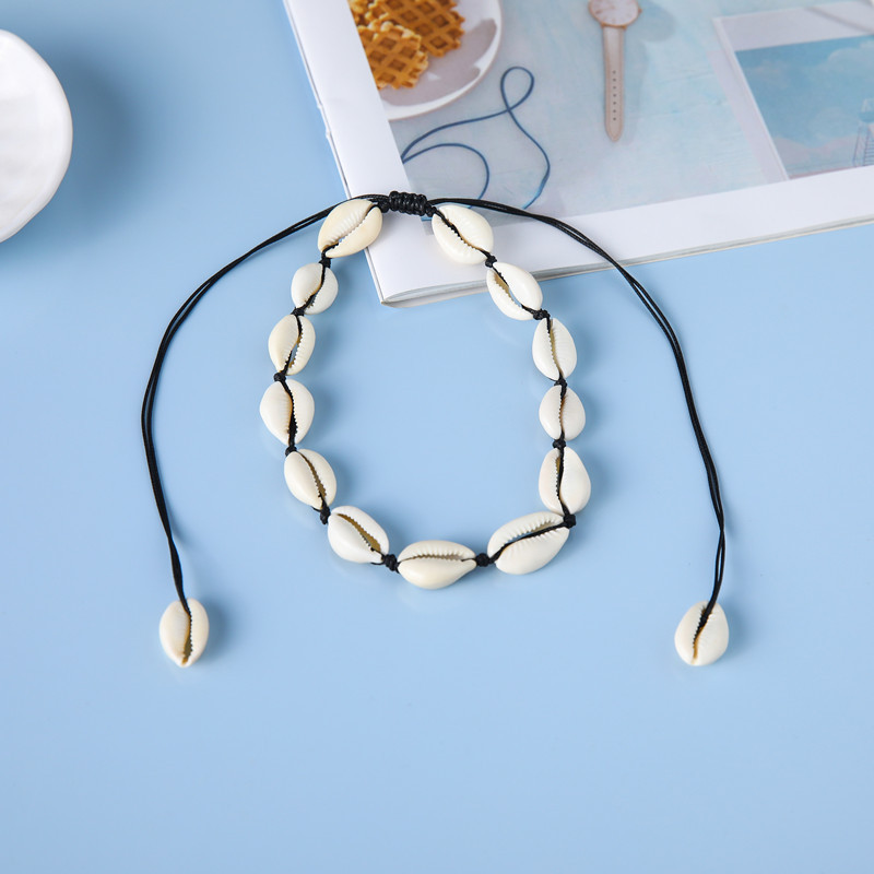 Coquillages blancs tissés avec du fil noir