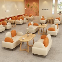 Canapé deux places minimaliste crème et orange avec dossier coussiné, table ovale en bois et table d'appoint ronde pour café et salon