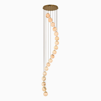 Lustre moderne en spirale pour escalier long, avec boules en albâtre naturel et structure métallique, idéal pour villa et hall à plafond haut