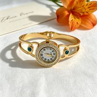 Montre bracelet pour femme à cadran rond incrusté de diamants, motifs ajourés multiples, bracelet en acier titane doré brillant