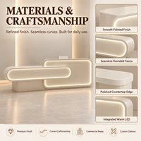 Comptoir d'accueil moderne pour salon de beauté, beige crème, asymétrique, double couche, façade arrondie avec éclairage LED chaud pour hall de spa
