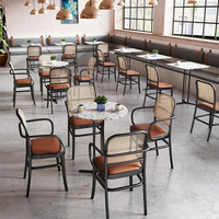 Chaises de salle à manger à dossier en cannage avec sièges rembourrés couleur caramel et tables en marbre avec base en piédestal noir pour café-bistro moderne