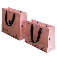 Élégantes boîtes cadeaux en papier rose avec ruban satiné et sac de transport pour vêtements féminins et solutions d'emballage pour bougies