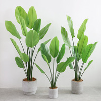 Décoration d'intérieur presque naturelle : palmiers et bananiers artificiels en pot, herbe verte et bonsaïs fleuris pour la décoration de la maison