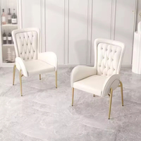Fauteuil moderne de luxe capitonné en cuir avec dossier haut et pieds en métal doré pour salle à manger