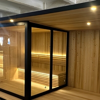 Sauna extérieur moderne avec douche de pluie intégrée, plateforme en bois, cadre noir, porte en verre, chauffage en pierre pour jardin et cour arrière