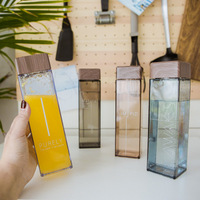 Bouteille d'eau réutilisable carrée en plastique avec couvercle en bambou, personnalisable avec logo, idéale pour les cadeaux promotionnels en gros