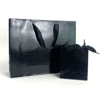 Sac en papier noir personnalisable avec motifs lézards et crocodiles, film brillant, sac cadeau haut de gamme et tendance pour magasin de vêtements