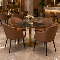 Ensemble table et fauteuils, surface en pierre frittée noire avec base en piédestal doré, mobilier pour café, terrasse et véranda