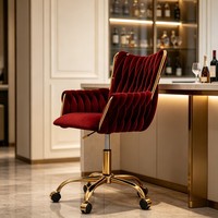 Fauteuil de détente en velours rouge, dossier haut capitonné, hauteur réglable, base pivotante en métal doré, roulettes