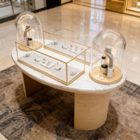 Table de présentation de bijoux de luxe avec plateau en marbre et pieds cylindriques en or brossé |   Vitrines en verre éclairées par LED avec socles en forme de dôme |   Personnalisable