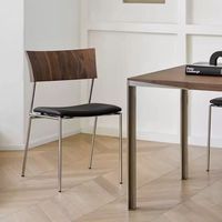 Chaise de salle à manger de style italien rétro de luxe épaissie, en acier inoxydable, avec accoudoirs en cuir véritable noir et assise rembourrée noire