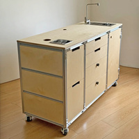 Meuble de cuisine mobile en profilé aluminium et contreplaqué marin, avec évier, tiroirs et roulettes, servant également de bar à café et d'îlot.