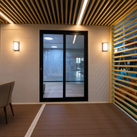 Studio préfabriqué moderne pour jardin avec terrasse à persiennes et porte vitrée, idéal pour fermes, complexes hôteliers et locations de vacances